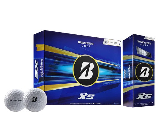 Zwei weisse Bridgestone Tour B XS Golfbälle liegen vor einer blau-goldenen Packung und einer schmalen Schachtel. Die Packung zeigt das Bridgestone Golf Logo, 'TOUR B XS' und den Hinweis auf 12 Bälle.
